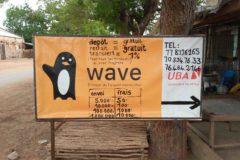 a sign post showing the wave logo and agency banking fees for various transactions