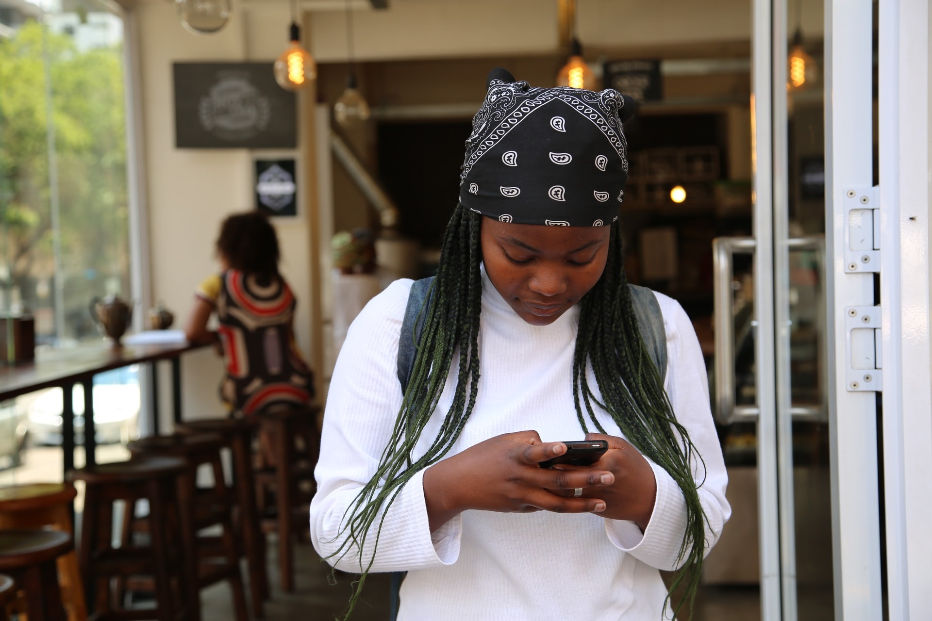 African young woman using a mobile phone in foreground in a building.