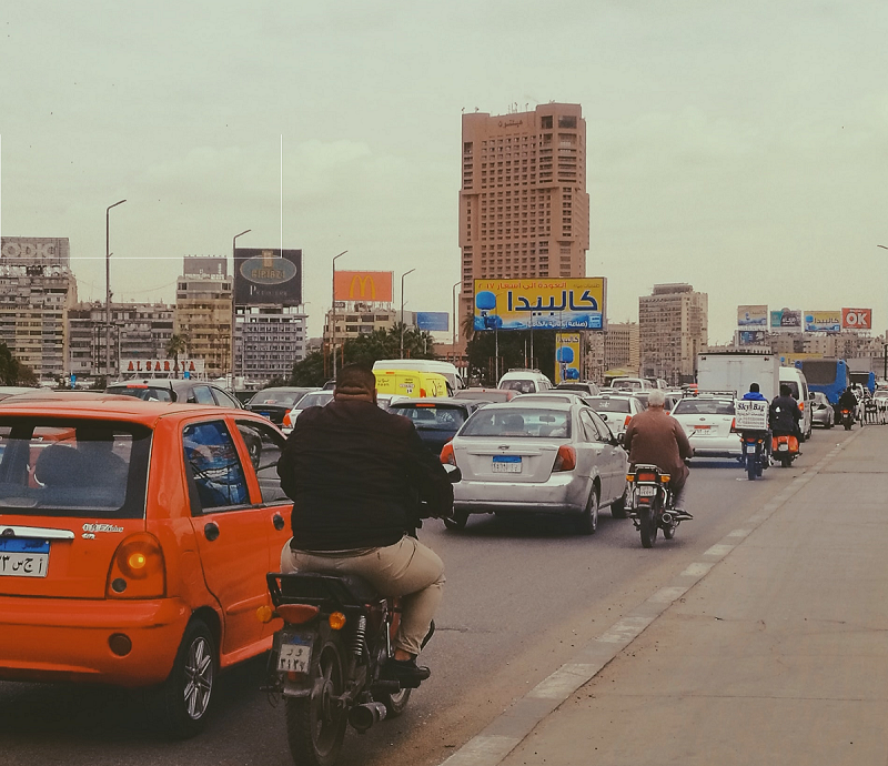 Motorists in Cairo. A scooter and a car share a lane on a roadway in Cairo