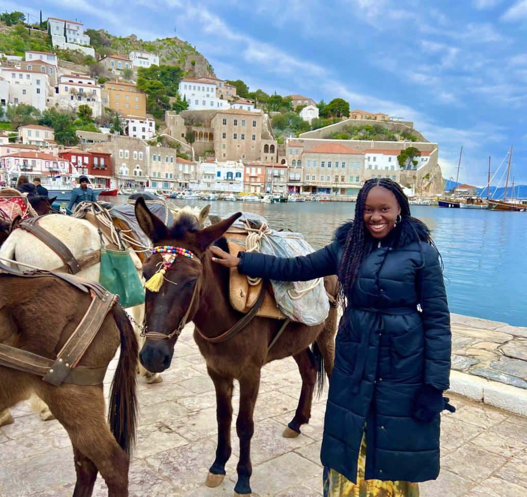 Picture of Odjugo smiling and standing next to a horse at Hydra Island, Greece.